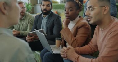 Çok ırklı bir grup erkek ve kadın birlikte çalışma merkezinde iş projesini konuşuyor. Çalışanlar iş fikirlerini paylaşıyor ve şirket kuruyorlar..