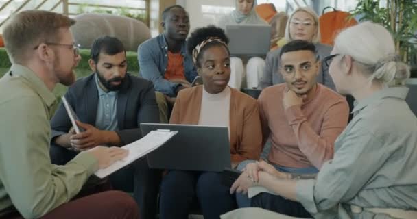同僚の多文化グループは コワーキングセンターで話すビジネスアイデアについて話し合っています 成功したチームワークとプロの活動コンセプト — ストック動画