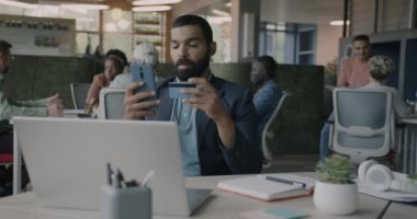 Güvenilir Ortadoğulu işadamı, ortak ofiste kredi kartıyla akıllı telefon kullanarak ödeme yapıyor. İş adamları ve finans kavramı.