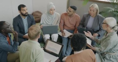 Dizüstü bilgisayarları ve iş belgeleriyle birlikte çalışma merkezindeki iş geliştirme çalışmalarını tartışan çok kültürlü bir grup iş arkadaşı. Modern insanlar ve takım çalışması kavramı.