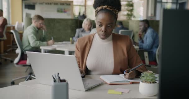 Ambitiös Afroamerikansk Affärskvinna Arbetar Med Bärbar Dator Och Skriva Forskning — Stockvideo