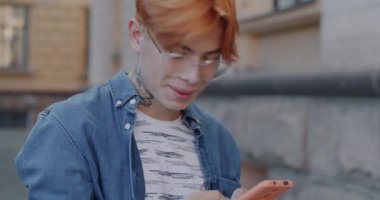 Mutlu Asyalı adam elinde akıllı telefonla internette sörf yapıyor ve gülümsüyor. Şehir caddesinde online içerikten keyif alıyor. Mobil uygulama ve aygıt kavramı.