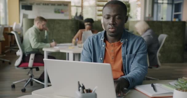 아프리카계 미국인 사업가 배경에서 동료와 센터에서 책상에서 노트북을 타이핑 — 비디오