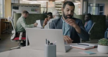 Orta Doğulu girişimci dizüstü bilgisayarla çalışıyor, daktilo ediyor ve ortak ofiste not tutuyor. İş bilgileri ve elektronik aygıtlar kavramı.
