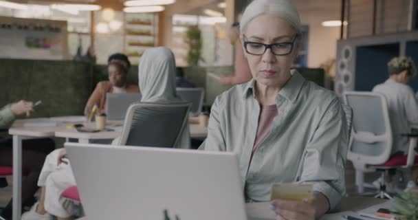 成熟的女商人在现代的协同工作空间用笔记本电脑和信用卡打字进行网上支付 财务和技术概念 — 图库视频影像