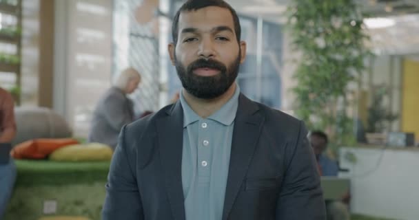 カメラを見ている同僚の場所に立っているスーツのひげ付き中東男性のゆっくりとした動きの肖像画 プロの職業と人々のコンセプト — ストック動画