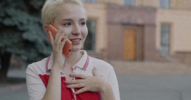 Yazın sokakta cep telefonuyla konuşan neşeli genç bir kadın. İletişim ve modern teknoloji kavramı.