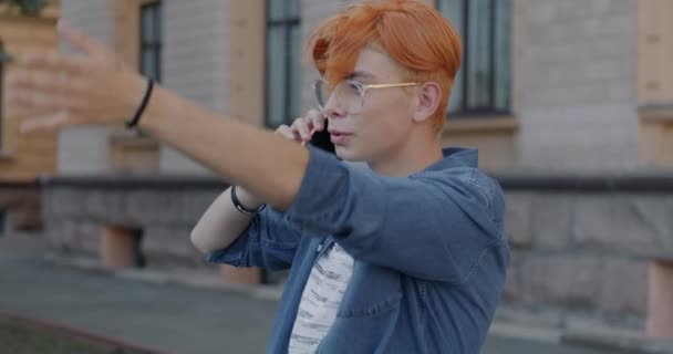 スタイリッシュな若いアジア人男性がダウンタウンのストリートに立っている携帯電話のジェスチャーでチャット コミュニケーションと現代技術のコンセプト — ストック動画