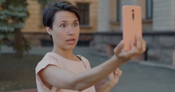 市内でエアキスを送信するスマートフォンでオンラインビデオ通話をする楽しい若い女性 バーチャルミーティングとガジェットのコンセプト — ストック動画