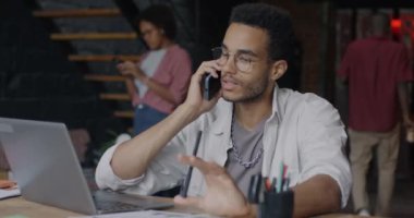 Neşeli bir Afrikalı Amerikalı girişimci cep telefonuyla iş tartışıyor çatı katında masa başı sohbetlerine odaklanıyor. İnsanlar ve iletişim konsepti.