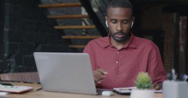 Afrika kökenli Amerikalı iş adamı internetten bilgisayar ve kulaklıkla iş görüşmesi yapıyor. İnsanlar ve sanal buluşma konsepti.