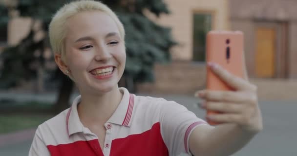 在城市里 无忧无虑的年轻女士在网上做视频通话时挥手说着智能手机的肖像 青年与小玩艺儿概念 — 图库视频影像