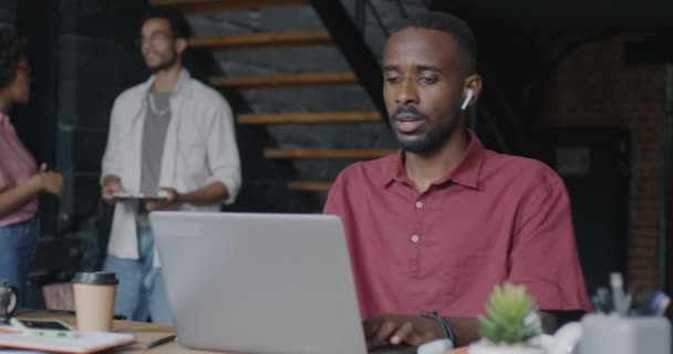 非裔美国商人在阁楼风格的办公室里用笔记本电脑工作 并通过耳机听音乐 人与专业职业概念 — 图库视频影像