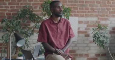 Başarılı Afrikalı Amerikalı girişimci kameraya dönüp çatı katı tarzı iş birliği merkezinde gülümsüyor. İnsanlar ve işyeri konsepti.