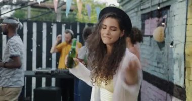 Caddedeki kafede dans eden, şişeden içen ve boş zamanlarında müzik dinleyen hoş bir kızın portresi. Aktif yaşam tarzı ve gençlik kültürü kavramı.