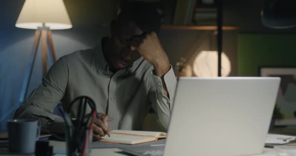 Jovem Afro Americano Escrevendo Notebook Planejando Negócios Trabalhando Escritório Escuro — Vídeo de Stock