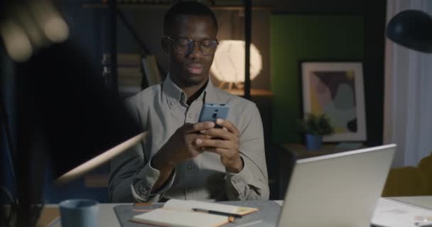 Afrikalı Amerikalı Serbest Çalışan Akıllı Telefon Kullanan Müşteriyle Konuşan Geceleri — Stok video