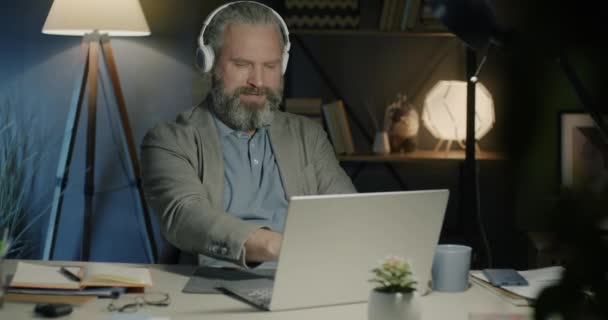 Radosny Biznesmen Słuchający Muzyki Słuchawkami Śpiewającymi Tańczącymi Pracującymi Nocy Laptopem — Wideo stockowe