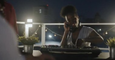 Mutlu Afrikalı Amerikalı DJ gece çatıdaki kalabalığa müzik çalıp şarkı söylüyor. Eğlence ve gece hayatı konsepti.