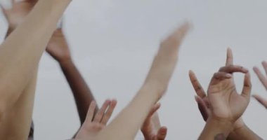 Bir grup insan dışarıda dans ederken ellerin gökyüzü arka planına doğru hareket ettiği yakın plan. Eğlence ve arkadaşlık konsepti.