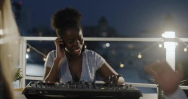 Gecenin bir yarısı erkekler ve kadınlar çatıda dans ederken neşeli kadın DJ 'in müziği. Modern yaşam tarzı ve eğlenceli gece hayatı konsepti.