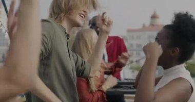 Kaygısız öğrenciler çatıda açık hava partisinin tadını çıkarırken DJ de yaz günü modaya uygun müzik çalıyor. Mutlu gençlik ve eğlence etkinliği konsepti.