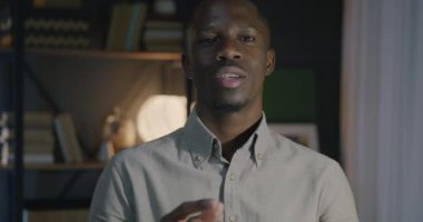 Afrika kökenli Amerikalı iş adamının portresi. Gece ofisindeki kameraya bakarak onay veriyor ve onayı veriyor. İş ve iletişim konsepti.