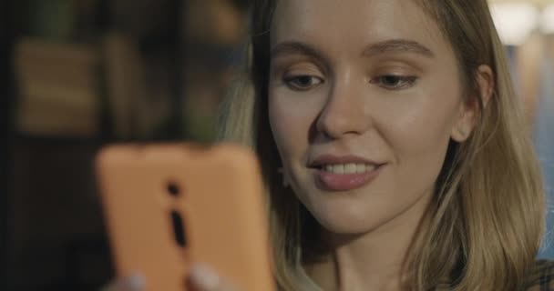 スマートフォンのチャットを使用して幸せな若い女性のズームアウトの肖像画は 自宅で夜にガジェットを楽しんでいます テクノロジーと若者のコンセプト — ストック動画