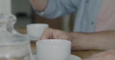 Eşcinsel çiftin kahvaltısını yaparken, erkeğin taze kahveyi bardağa doldurduğu yakın plan. Mutfak konseptinde kafein içeceği ve yemek.