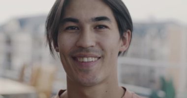 Bulanık şehir geçmişine gülümseyen neşeli Asyalı kişinin yakın plan portresi. Gençler için neşeli öğrenci ve şehir yaşam tarzı.