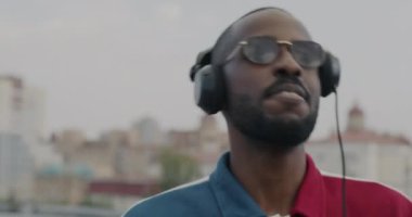 Erkek DJ kulaklık takıyor miksaj ekipmanı kullanıyor açık hava partisinde müzik yapıyor. Çağdaş teknoloji ve eğlence kavramı.