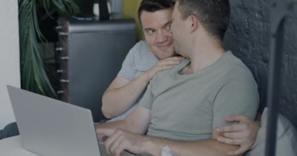 快乐的同性恋夫妇穿着睡衣坐在床上聊天 拥抱在一起 同性家庭生活方式和现代技术概念 — 图库视频影像