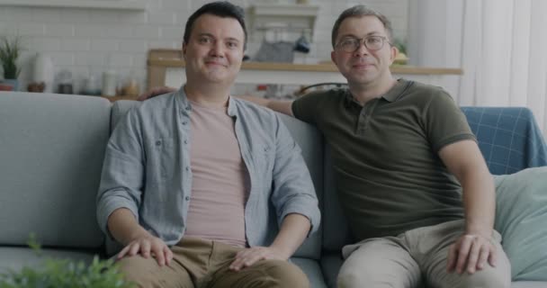 Dos Hombres Jóvenes Pareja Gay Sentado Sofá Apartamento Sonriendo Mirando — Vídeo de stock