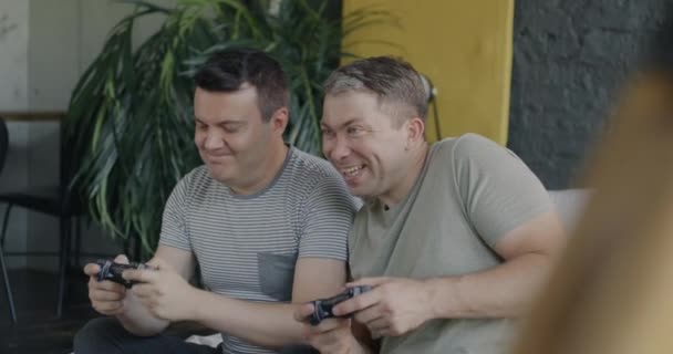 楽しいゲイカップルは 家でベッドに座っているジョイスティックを使用してハイファイブを勝ち取るビデオゲームをプレイしています エンターテインメントとLgbtqコンセプト — ストック動画