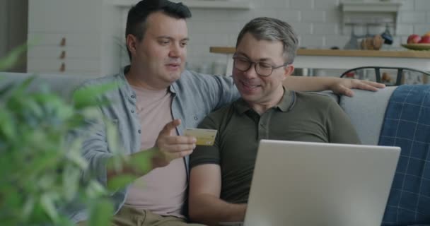 Fröhliches Gleichgeschlechtliches Paar Das Mit Laptop Und Kreditkarte Online Einkauft — Stockvideo