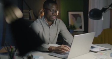 Bilgisayarla çalışan Afro-Amerikan çalışanlar karanlık ofiste gece vardiyası işine yoğunlaşmışlar. Başarılı insanlar ve mesleki işgal kavramı.