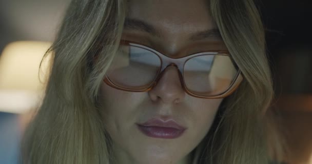 戴着时髦眼镜的女性面部特写集中在晚上的办公室工作上 工作到很晚 忙着用计算机上网的女商人 戴眼镜也不例外 — 图库视频影像
