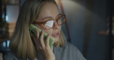 Genç iş adamının portresi cep telefonuyla iş tartışıyor ve gece ofiste sohbete odaklanıyor. İş ve telefon görüşmesi konsepti.