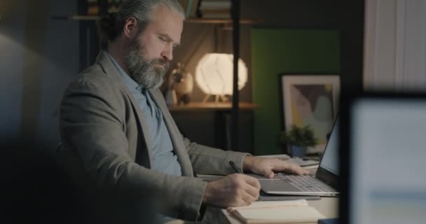 Middle Aged Businessman Writing Information Notebook Looking Laptop Screen Working — Stock Video