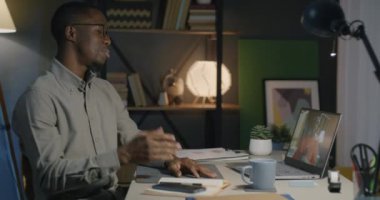 Afrika kökenli Amerikalı iş adamları geceleri bilgisayarla ofiste sanal toplantı sırasında iş konuşuyorlar. Video çağrısı ve iş konsepti.