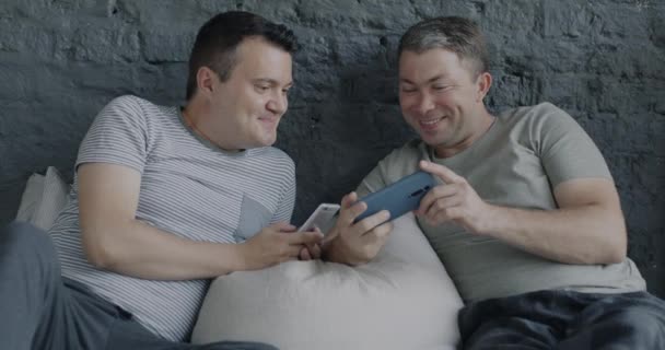 使用智能手机的无忧无虑的男同性恋躺在床上聊天 享受在一起的闲暇时光 Lgbtq关系和现代小玩意概念 — 图库视频影像