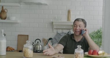 Kocası evde yemeğin tadını çıkarırken cep telefonuyla konuşan bir adam. Aynı cinsiyetten aile ve aile hayatı kavramı.