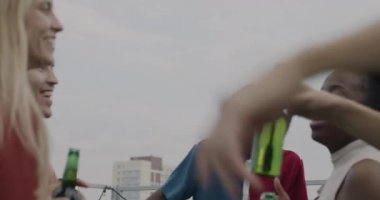 Arkadaşlar milenyum dansı yapıyor, bira şişelerini tokuşturuyor, alkol içiyor ve çatı partisinin tadını çıkarıyorlar. Modern yaşam tarzı ve kutlama konsepti.