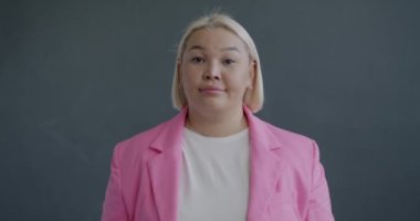 Hayal kırıklığına uğramış Asyalı iş kadınının gri arka planda el hareketi gösteren yavaş çekim portresi. İnsanlar ve olumsuz duygu kavramı.