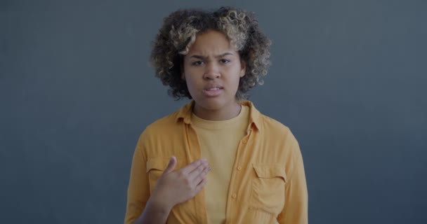 不満なアフリカ系アメリカ人女性のゆっくりとした動きの肖像画が自分自身を指差し 灰色の背景でカメラを見るオファーを拒否する腕を横断する — ストック動画