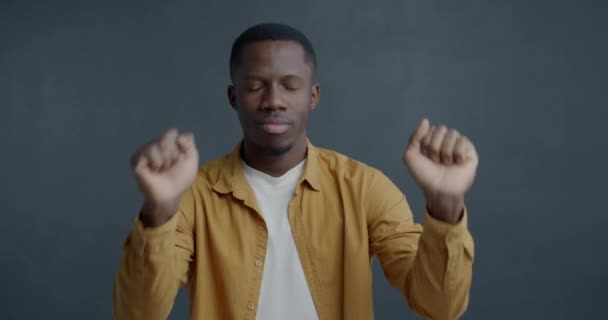 ハッピーなアフリカ系アメリカ人の男性のゆっくりとした動きの肖像画は グレーの背景で音楽を楽しんで閉じた目で踊っています 人と若者の文化コンセプト — ストック動画