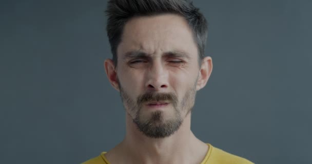 怒った顔をして 灰色の背景にネガティブな感情を表す歯を示す怒った男のクローズアップ写真 人と人の反応のコンセプト — ストック動画