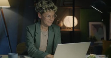 Dizüstü bilgisayarla çalışan genç ve güzel bir bayanın portresi. Sonra kameraya bakıp geceleri gülümsüyor. Serbest meslek ve mesleki meslek kavramı.