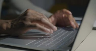 Afrika kökenli Amerikalı programcı geceleri masa başında yazarken, erkek ellerinin dizüstü bilgisayarla yazışmalarını yakından çek. Yazılım ve teknoloji kavramı.