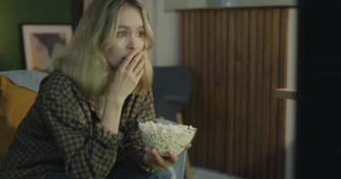 Duygusal genç kadın korku filmi seyrediyor ve geceleri karanlık evde patlamış mısır yiyor. Kitle iletişim araçları ve duygu kavramı.